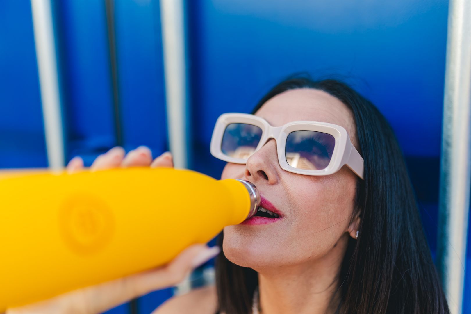 Mulher com óculos de sol a beber água de uma garrafa térmica cool bottles