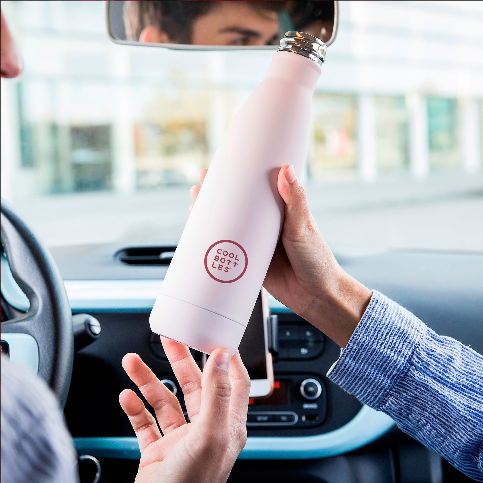 Duas pessoas com uma garrafa térmica rosa da Cool Bottles dentro do carro