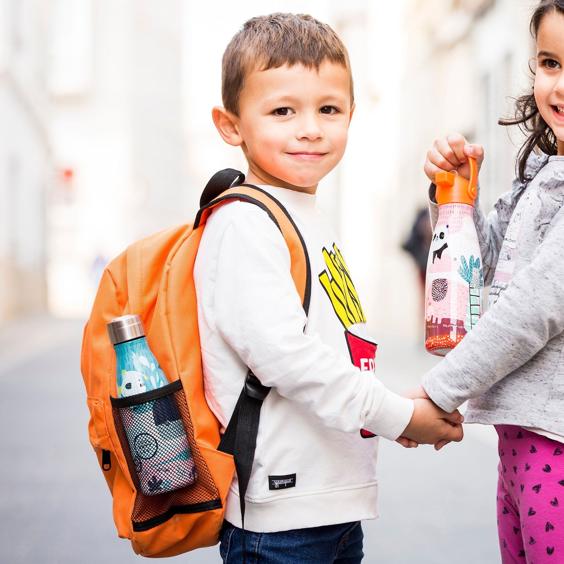 Rapaz e rapariga de mãos dadas com garrafas térmicas da Cool Bottles