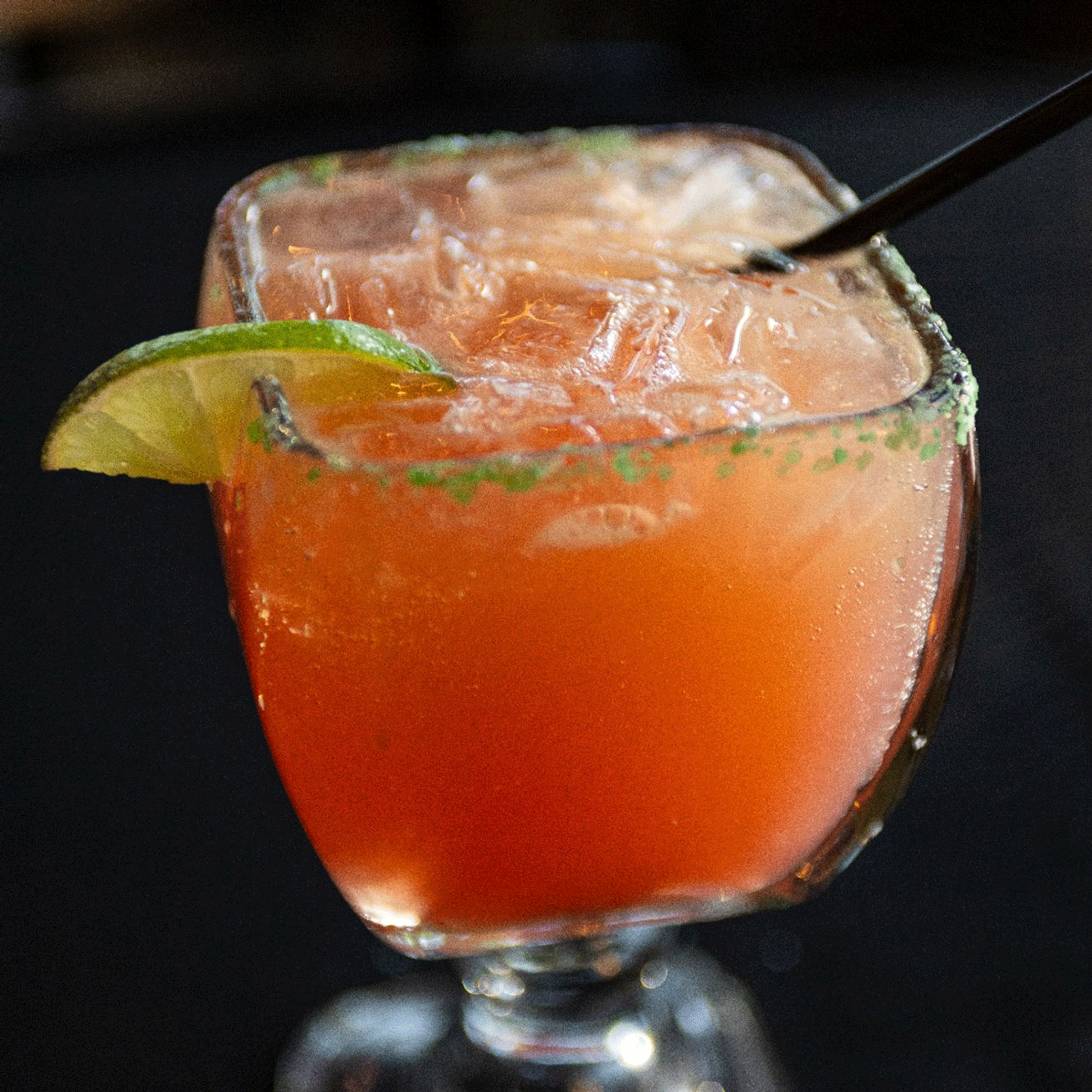 A margarita with a lime wedge garnish, rimmed with green salt.