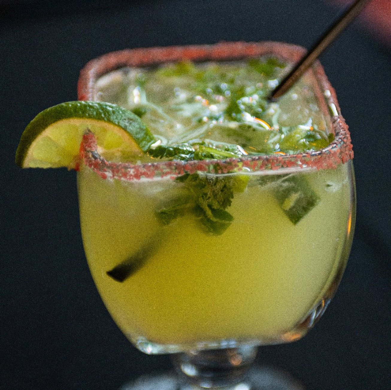 Lime margarita in a glass with a salt-rimmed edge, lime slice garnish, and a straw.