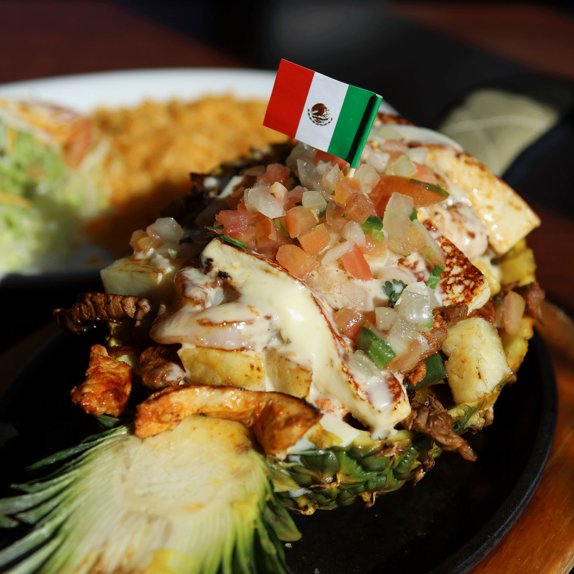 Pineapple boat with meat, cheese, and salsa, topped with Mexican flag.