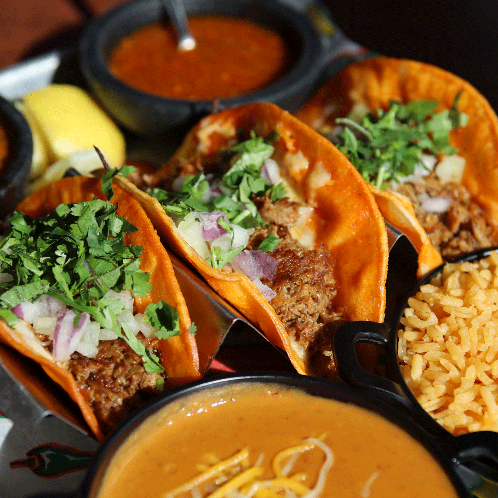 Tacos with meat, cilantro, and onions, served with salsa and rice.