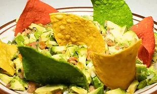 Bowl of diced avocado and beans, garnished with colorful tortilla chips.