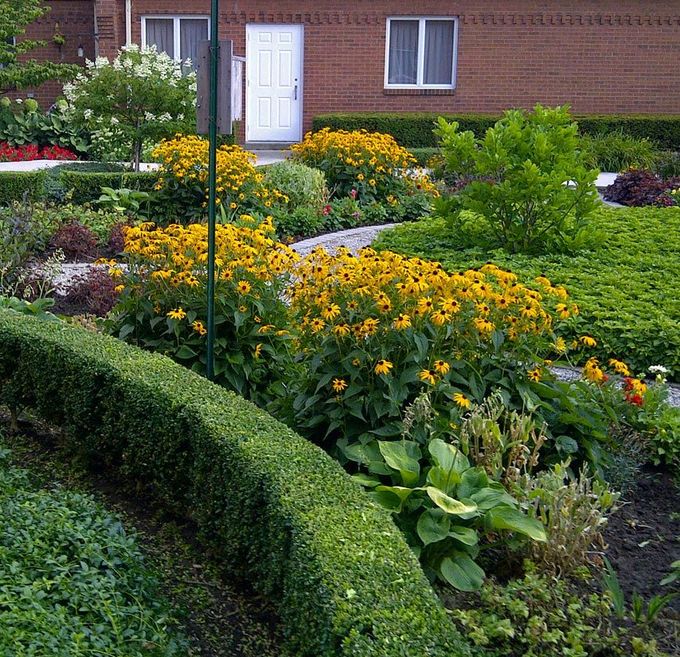 Riding lawn mower performing landscape maintenance