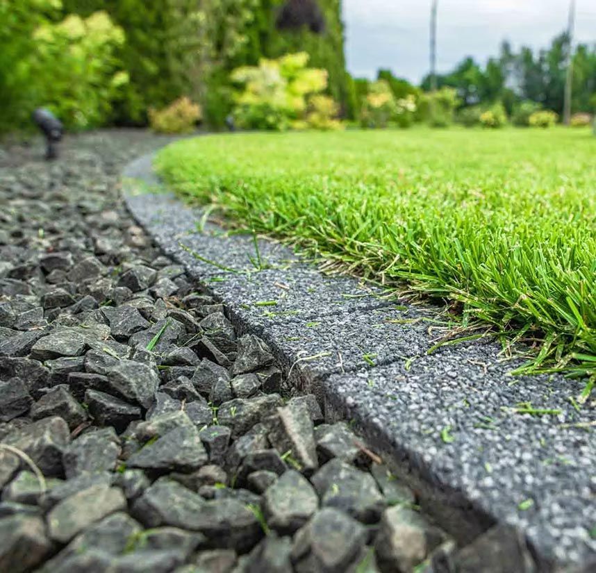 Well trimmed lawn with natural stone edge coping and crushed gravel filled garden bed