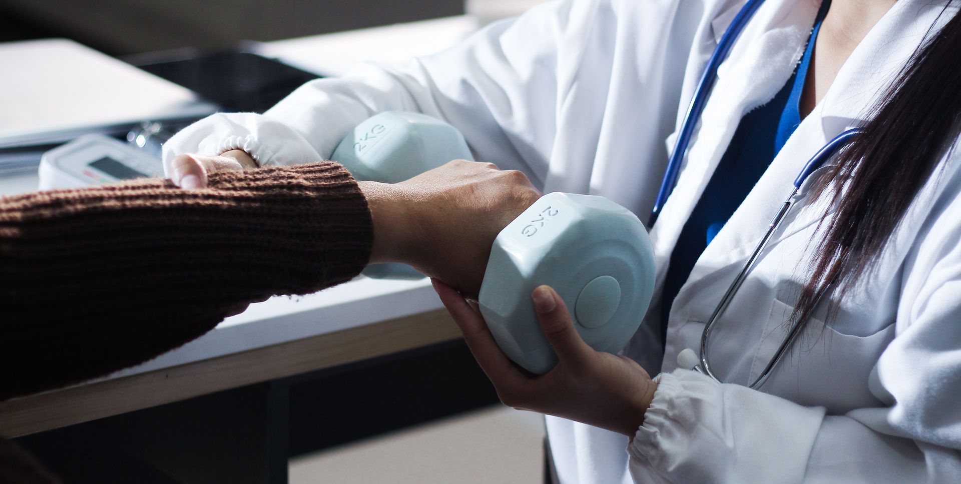 Gloved caregiver holds a patient’s hand in a clinic.