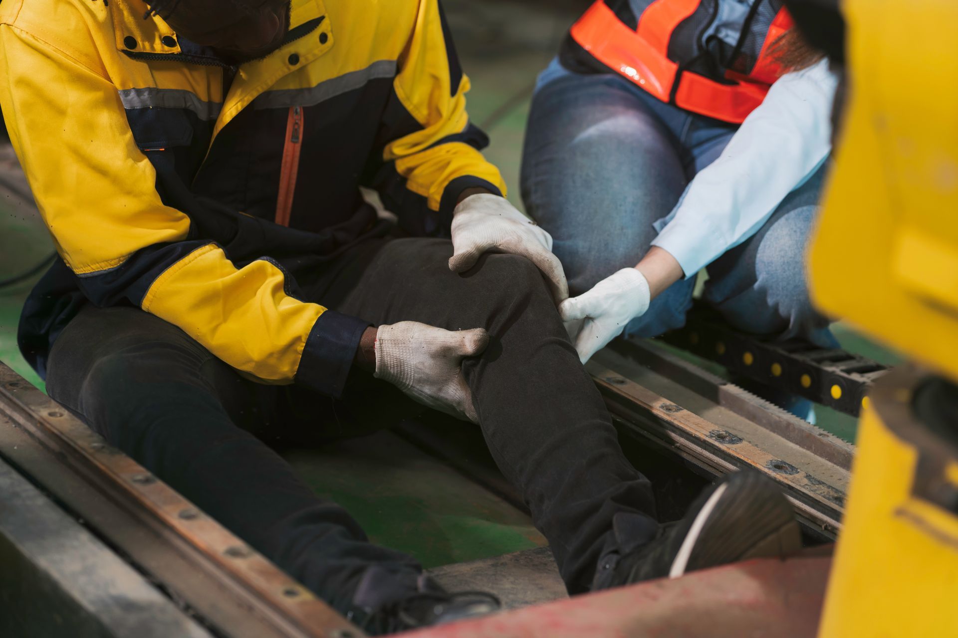 Rescuers in yellow jackets and gloves carry an injured person on a stretcher.