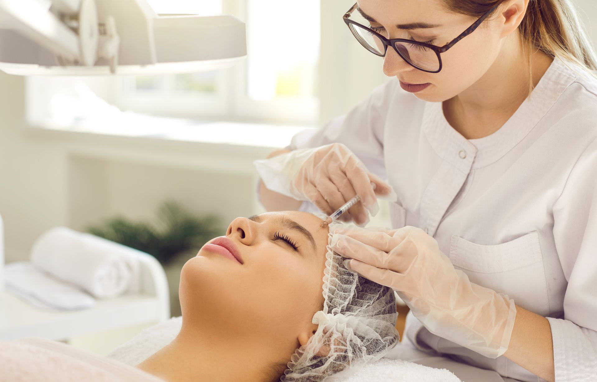A person receives a facial treatment. A professional in gloves injects the person's face. A person receives a facial treatment. A professional in gloves injects the person's face.
