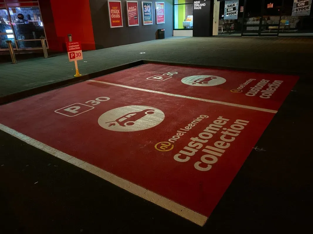 Red pavement marking for customer collection parking. Includes a car graphic, text, and time limit sign.