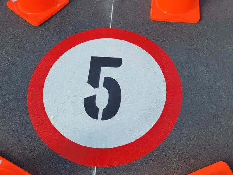 A circular road sign with a red border and a white center displays the number 5.