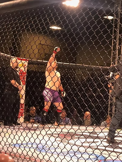 A man is standing in a cage with his fist in the air.
