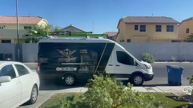White service van parked on a suburban street beside a blue trash bin, with houses in the background