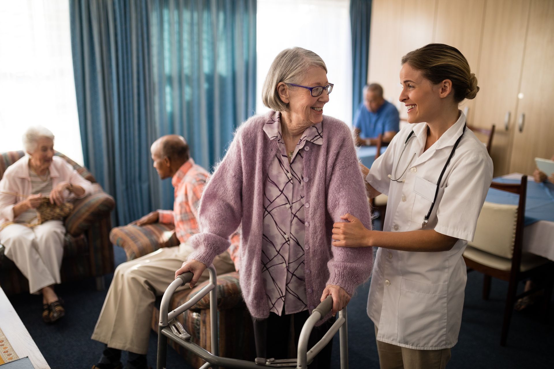 A female carer is helping an elderly woman put on a sweater in her home. A female carer is helping an elderly woman put on a sweater in her home.