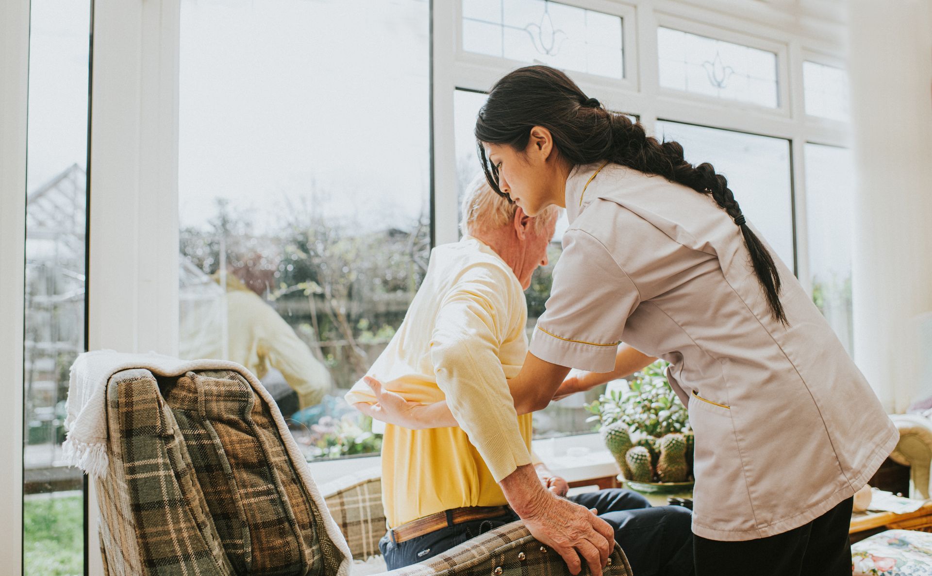 A young female carer helps an elderly male. Home care aide assisting senior man – Milford OH