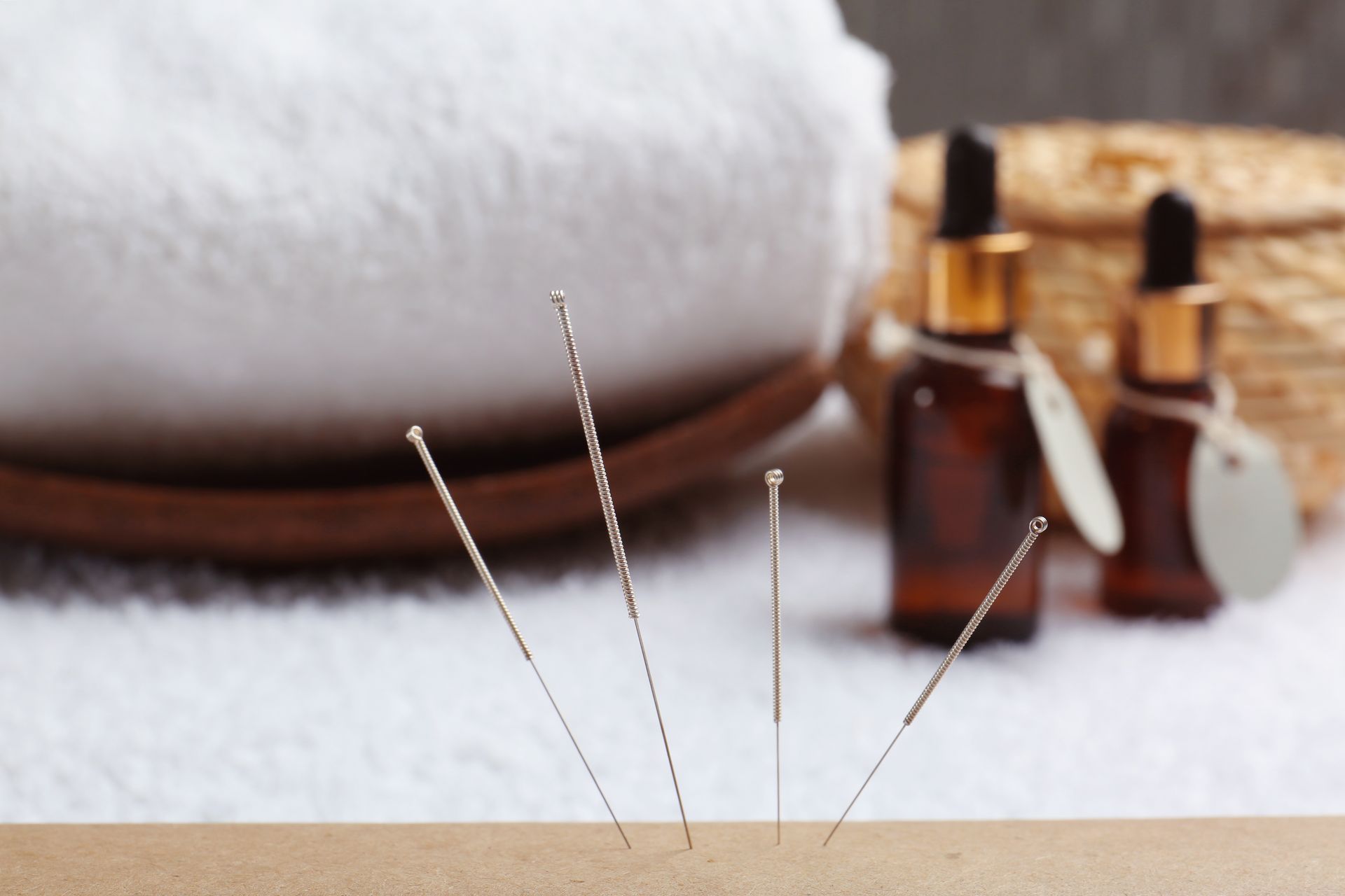 Acupuncture needles used for acupuncture for fertility sitting on a table next to bottles of essential oil.