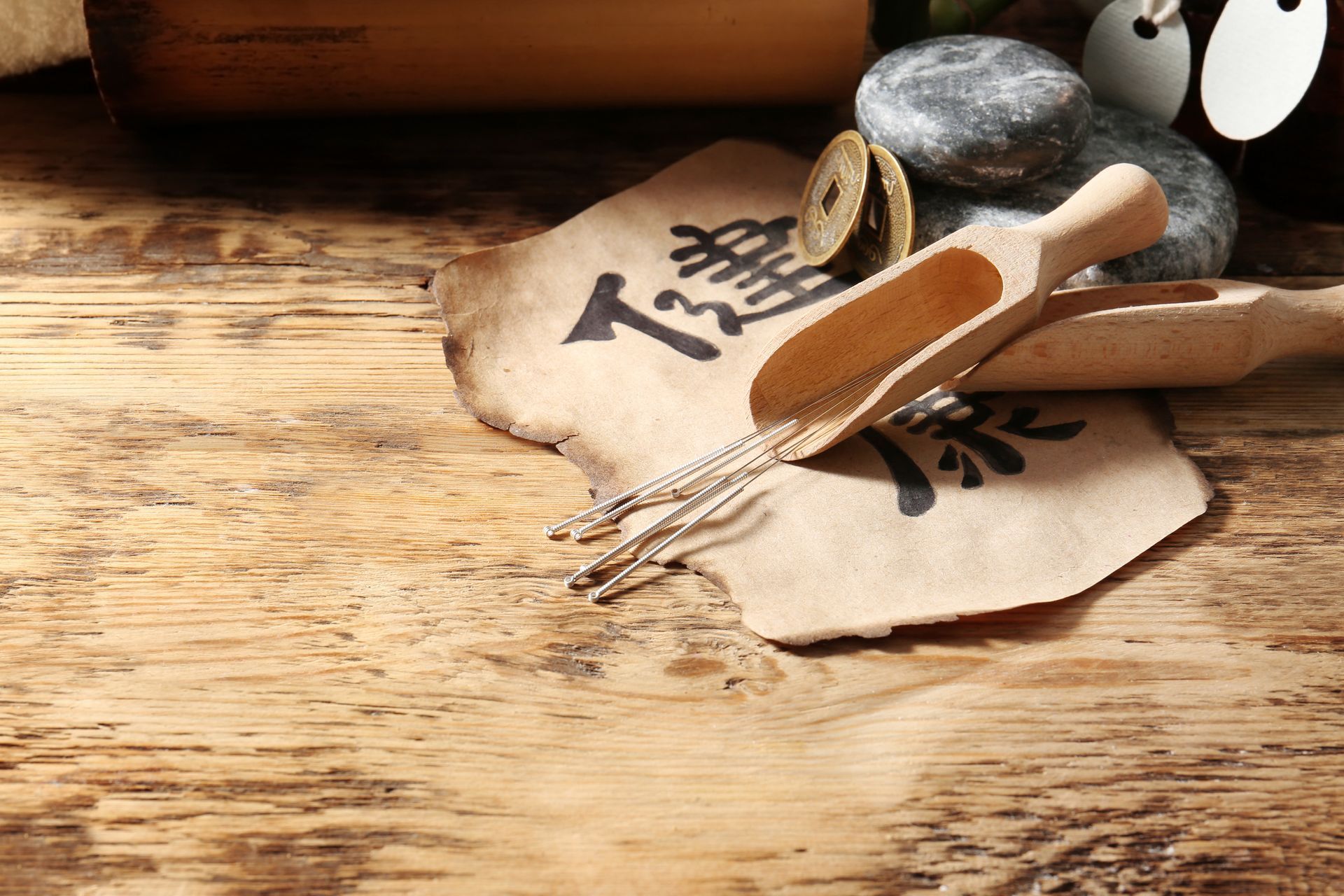 A wooden table with a spoon , acupuncture needles used for acupuncture for fertility, coins , and a piece of paper.