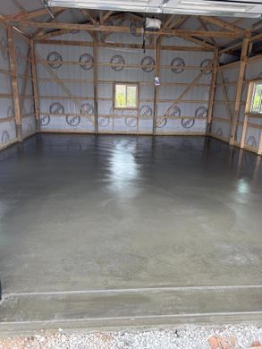 Empty unfinished room with a freshly poured concrete floor and exposed wall insulation.