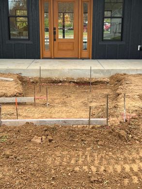Front of a house with a wooden double door and a bare, graded front yard under construction
