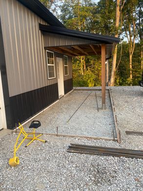 Gravel patio beside a house with a covered porch and yellow extension cord.