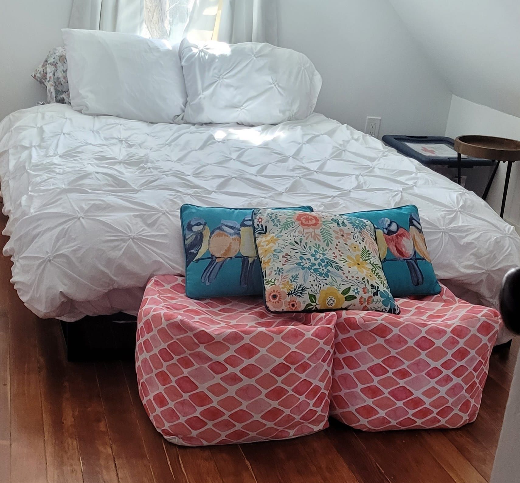 A bedroom with a bed and two pillows on ottomans