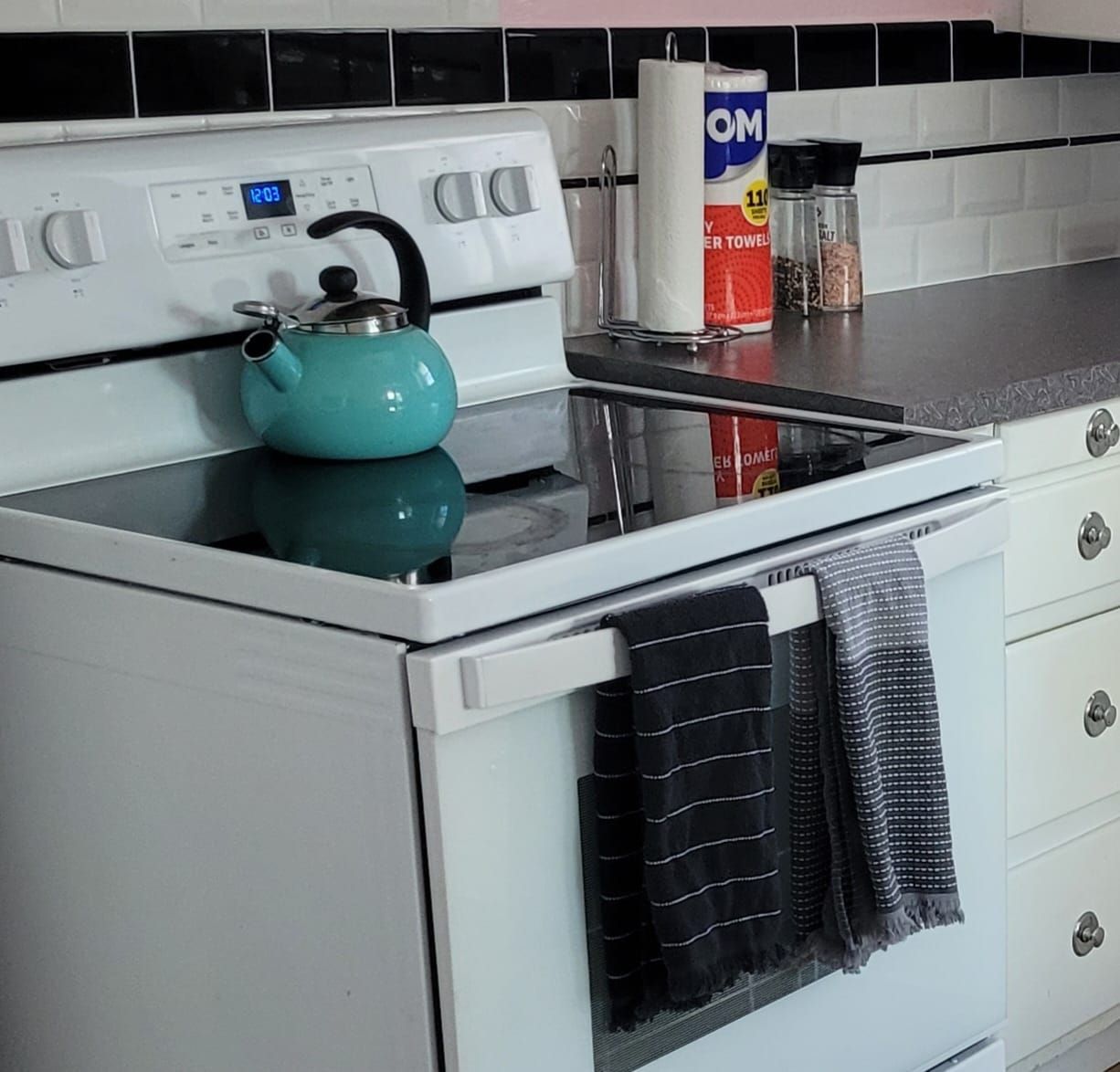 A blue tea kettle sits on top of a white stove in a kitchen