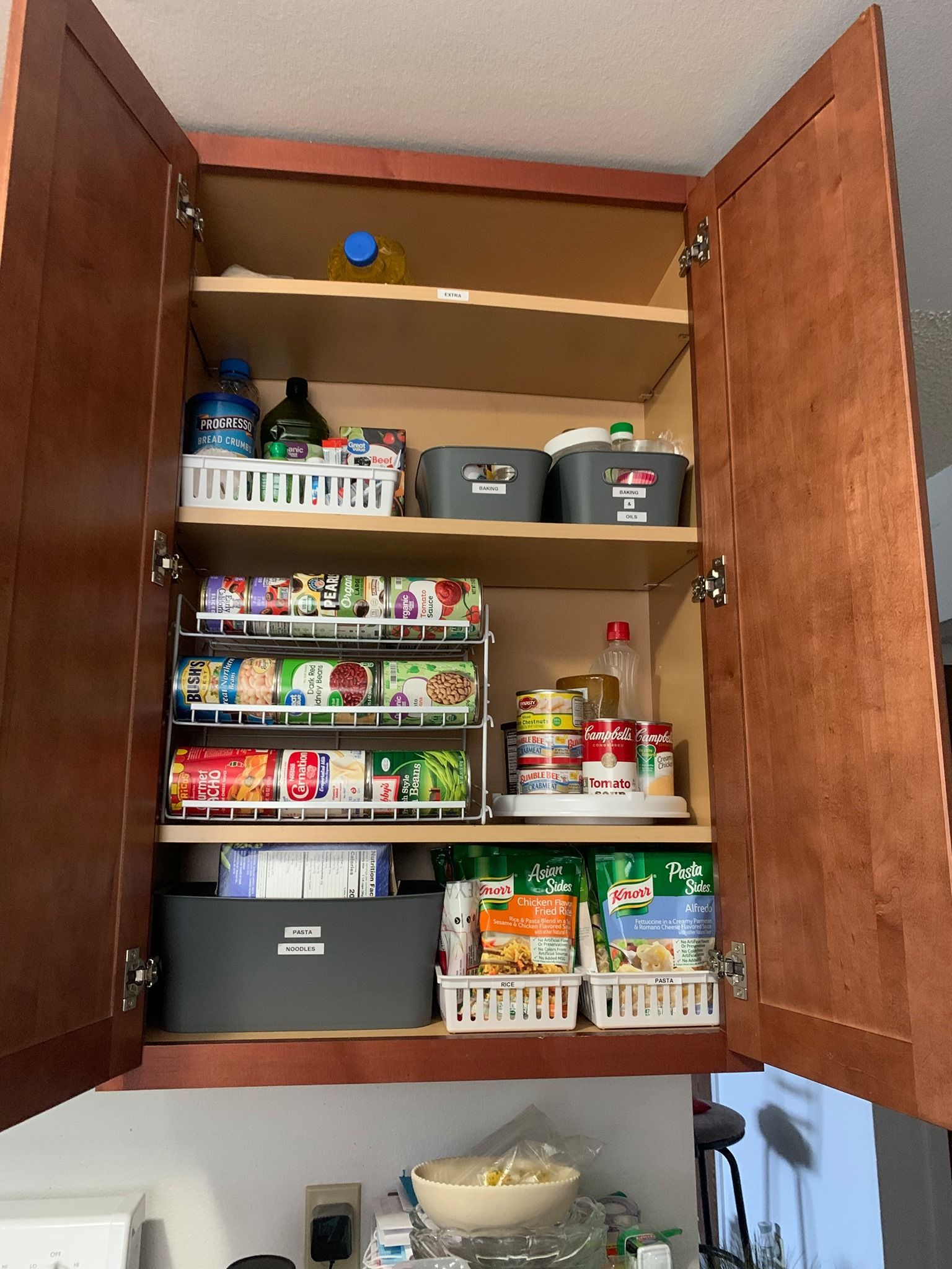 A kitchen cabinet filled with lots of food and supplies.