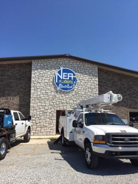 A white bucket truck parked in front of a stone building with a circular 