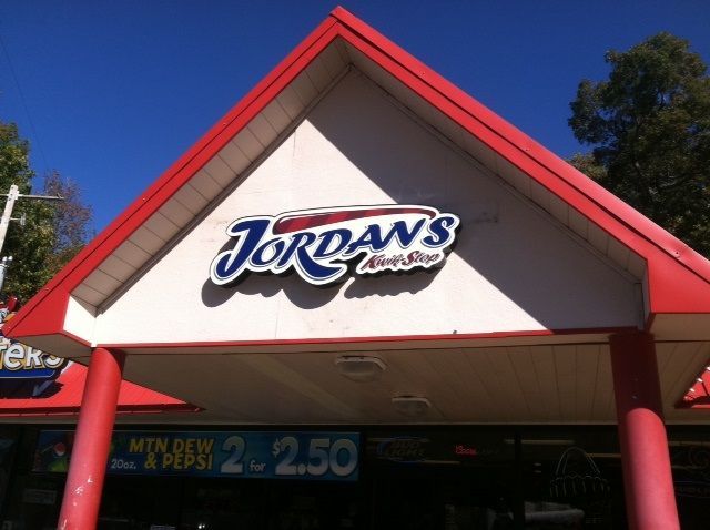 A bright, triangular-roofed Jordan's Kwik Stop convenience store with a Mtn Dew and Pepsi sale sign below.