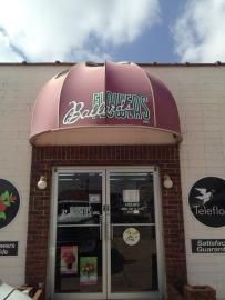 A storefront with a maroon awning labeled 