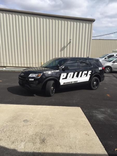 A black Manchester police SUV parked on asphalt in front of a metal-walled building.