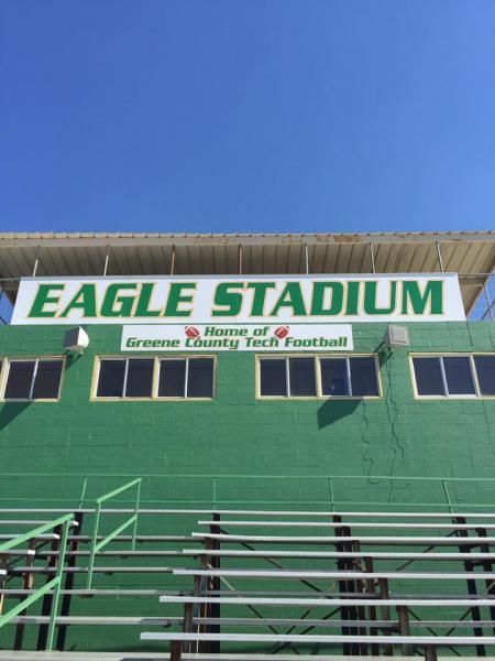 The press box at Eagle Stadium, home of Greene County Tech Football, sits above green stadium seating under a clear sky.