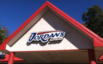 A triangular white building exterior with red trim featuring a blue and white 