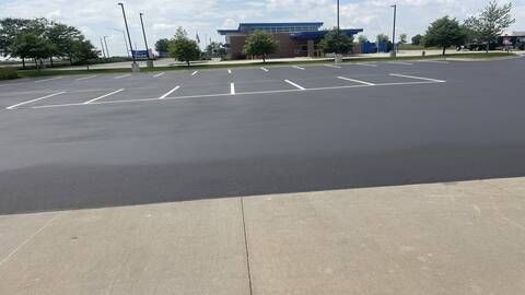 Empty parking lot with white parking lines in front of a building on a sunny day