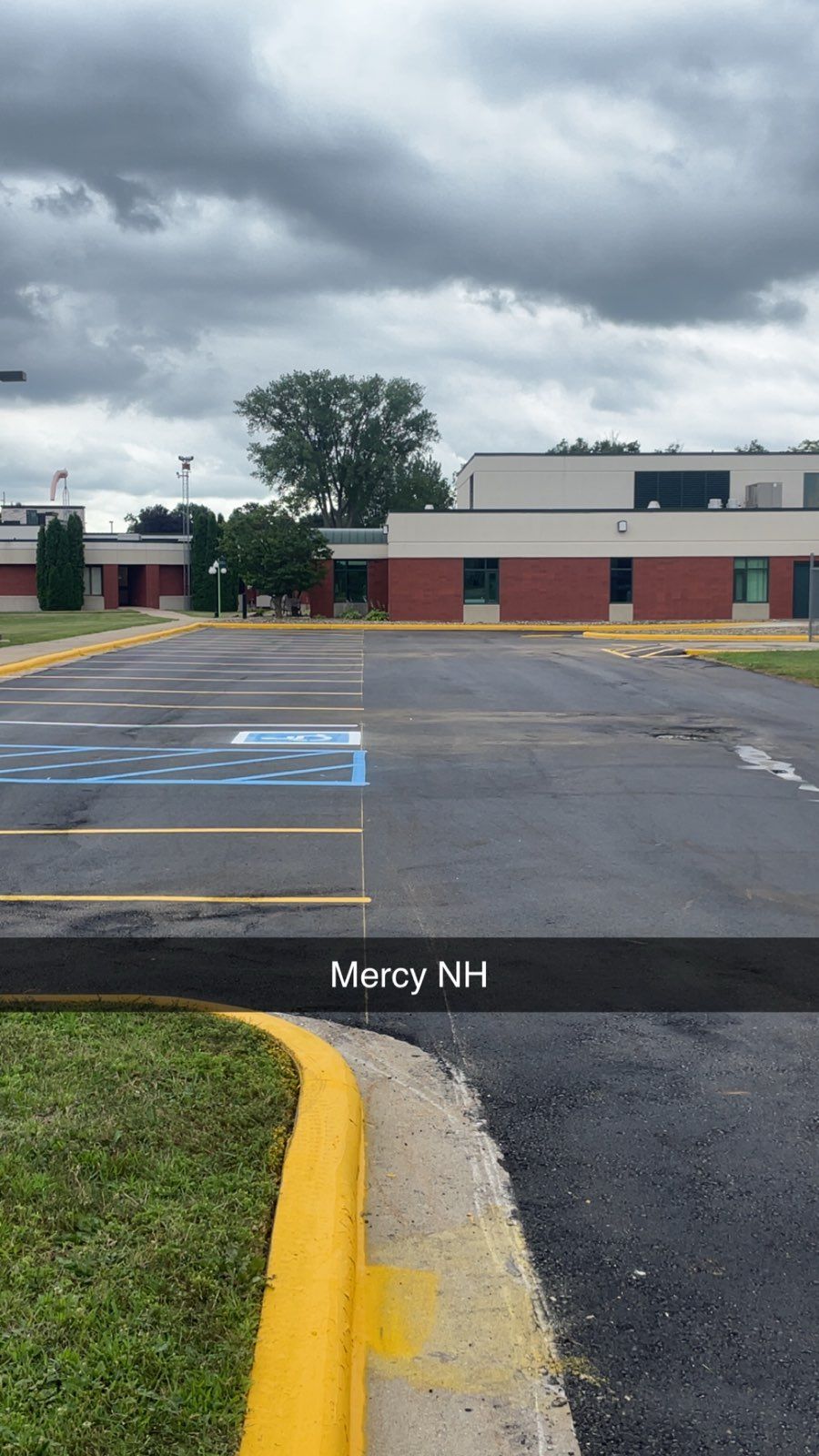 Empty parking lot outside a low brick building under cloudy skies