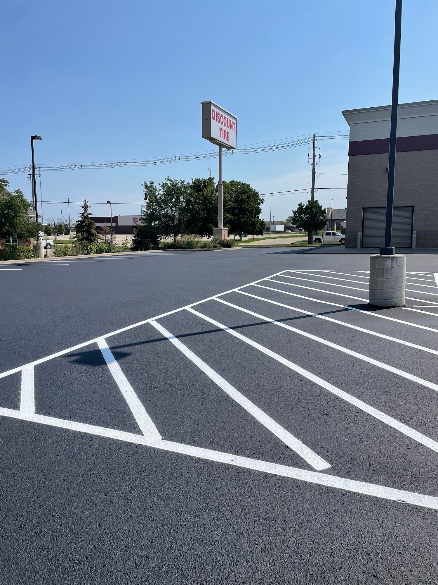 Empty parking lot with white diagonal striped no-parking zone and a building in the background