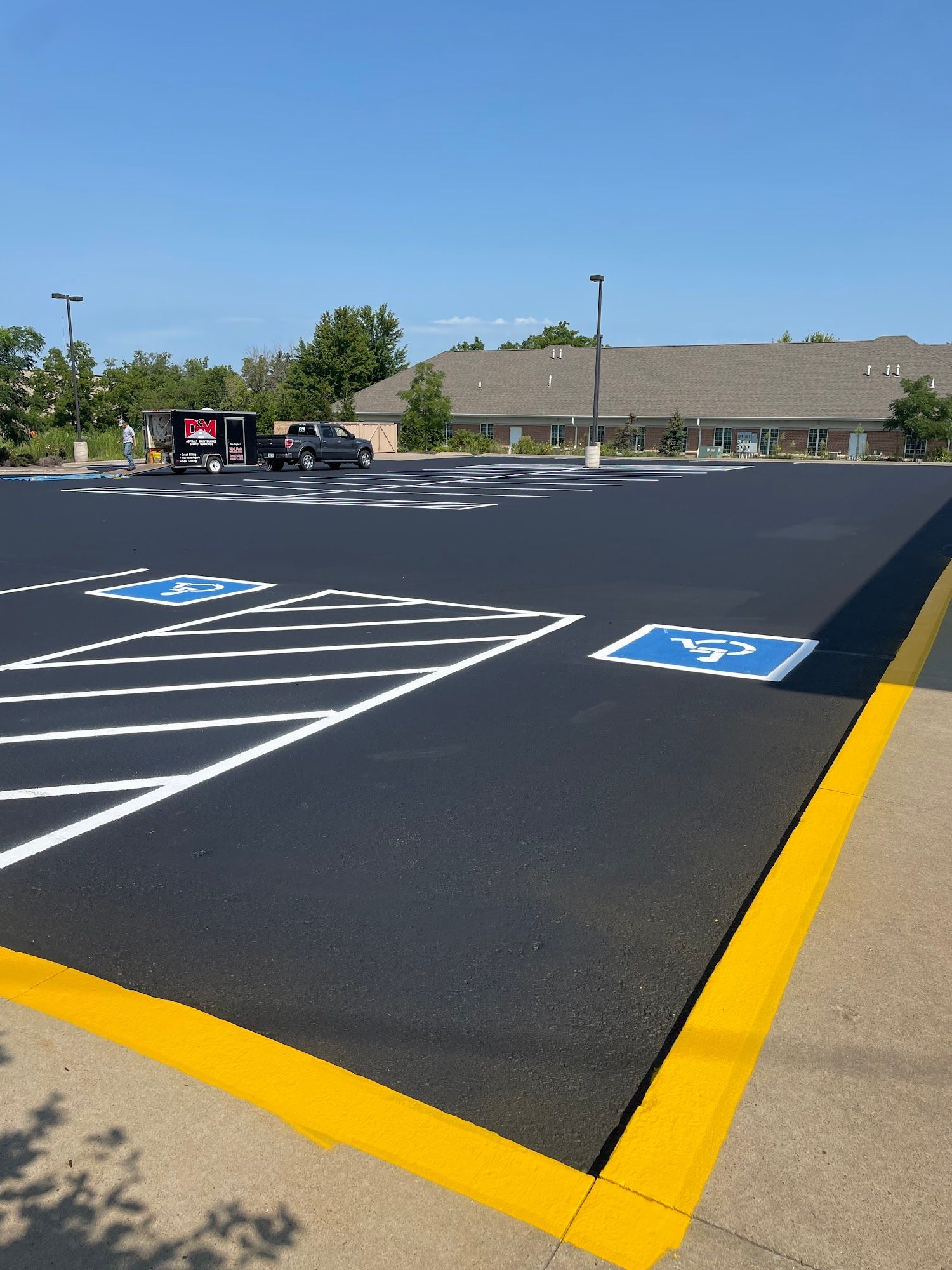 Empty accessible parking lot with blue wheelchair spaces and yellow curbs under a clear sky