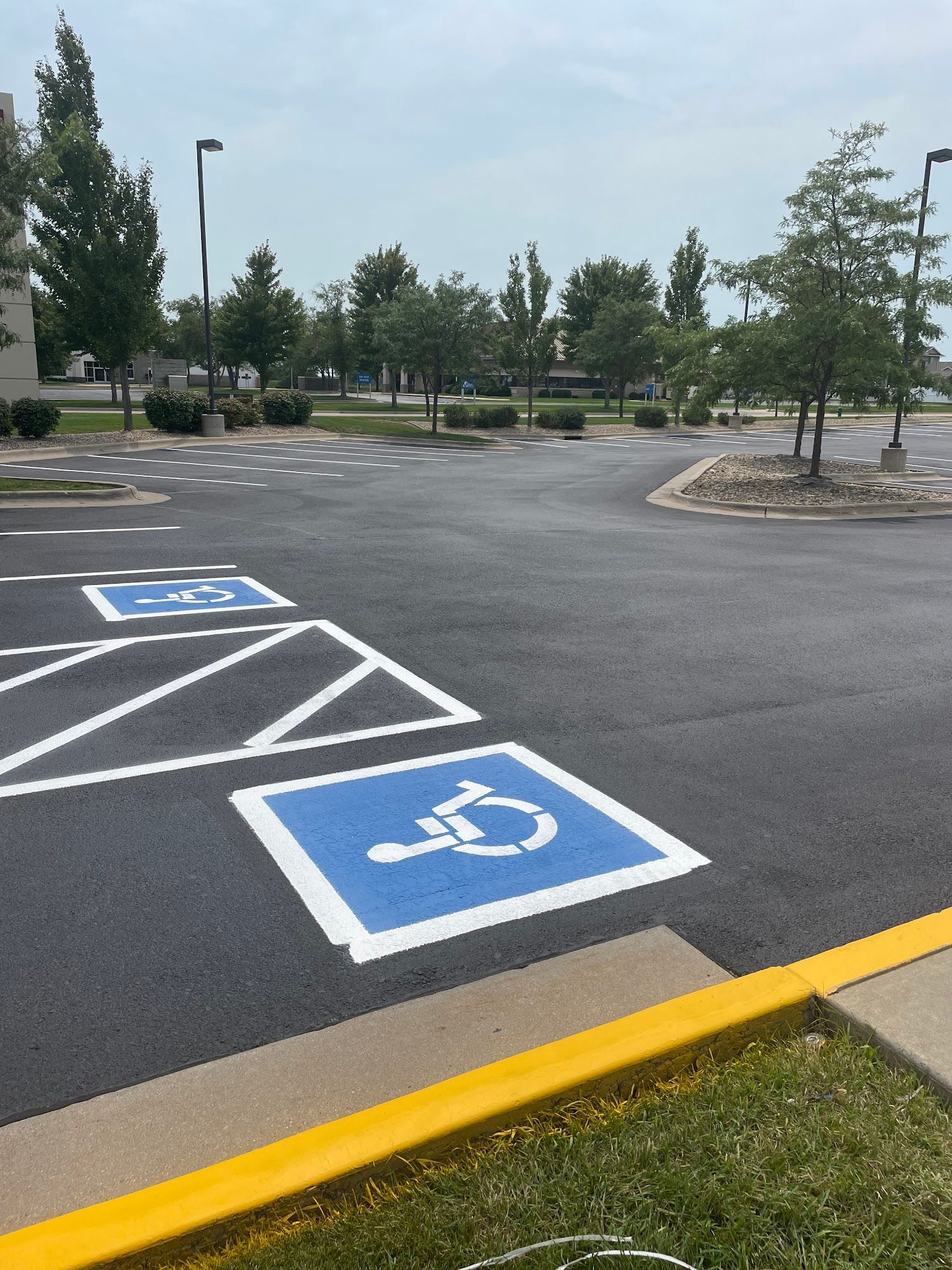 Accessible parking spaces in a mostly empty asphalt lot, marked with blue wheelchair symbols and yellow curb.