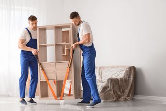 Workers carrying a large appliance into a home