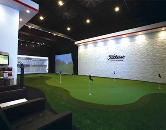 Indoor golf simulator with putting green, a screen, and the Titleist logo.