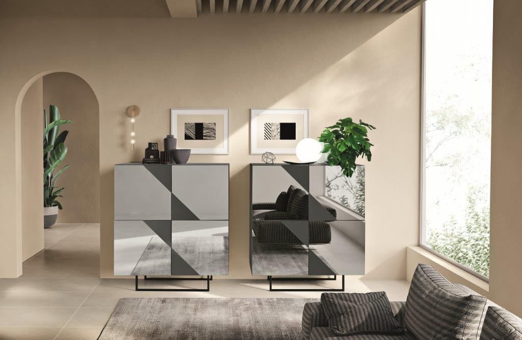 Due armadietti geometrici con specchio in una stanza con pareti neutre, opere d'arte e un divano.