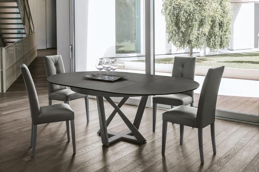 Tavolo da pranzo ovale grigio con quattro sedie grigie in una stanza moderna, vicino a una finestra.
