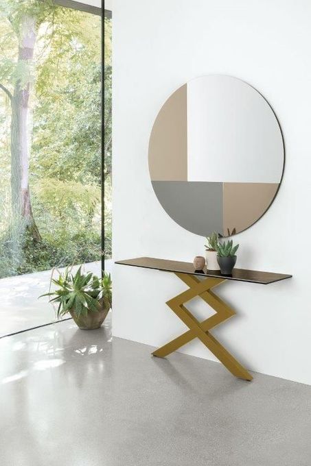 Consolle dorata a zig-zag con specchio decorativo su parete bianca.