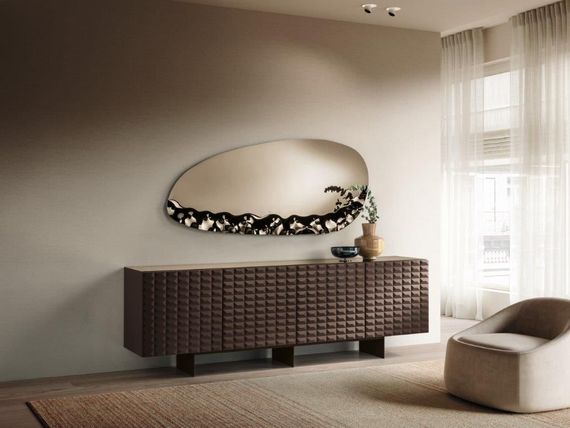 Un soggiorno moderno con un mobile marrone, uno specchio dalla forma organica e una poltrona beige.