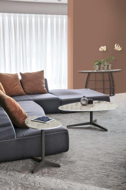 Soggiorno moderno con divano componibile blu, cuscini arancioni e due tavolini rotondi grigi su un tappeto grigio.