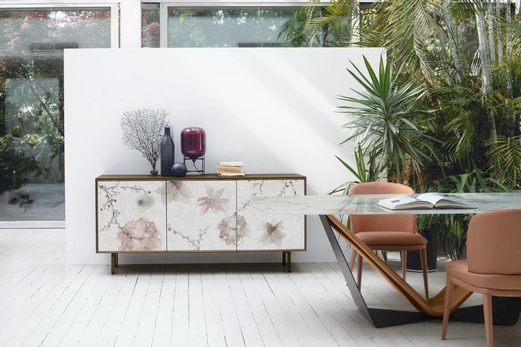 Credenza floreale con decorazioni in una sala da pranzo luminosa e luminosa, accanto a un tavolo con sedie e piante.