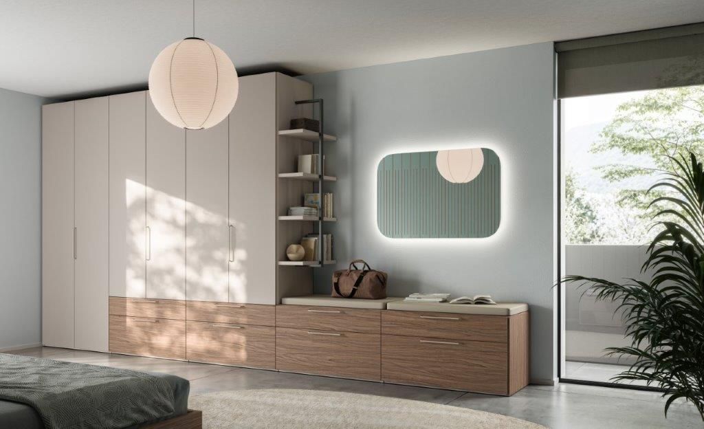Camera da letto con armadio a muro, cassetti, specchio e scaffali a giorno. Colori neutri, luce naturale.
