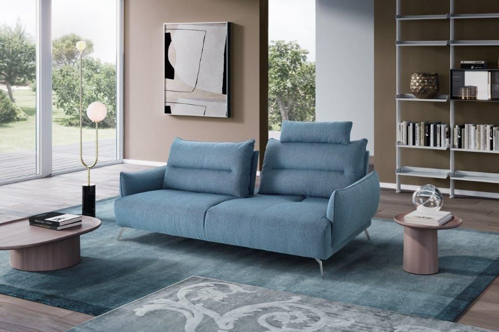 Divano blu in un soggiorno moderno con tappeto, quadri, mensole e lampada da terra.
