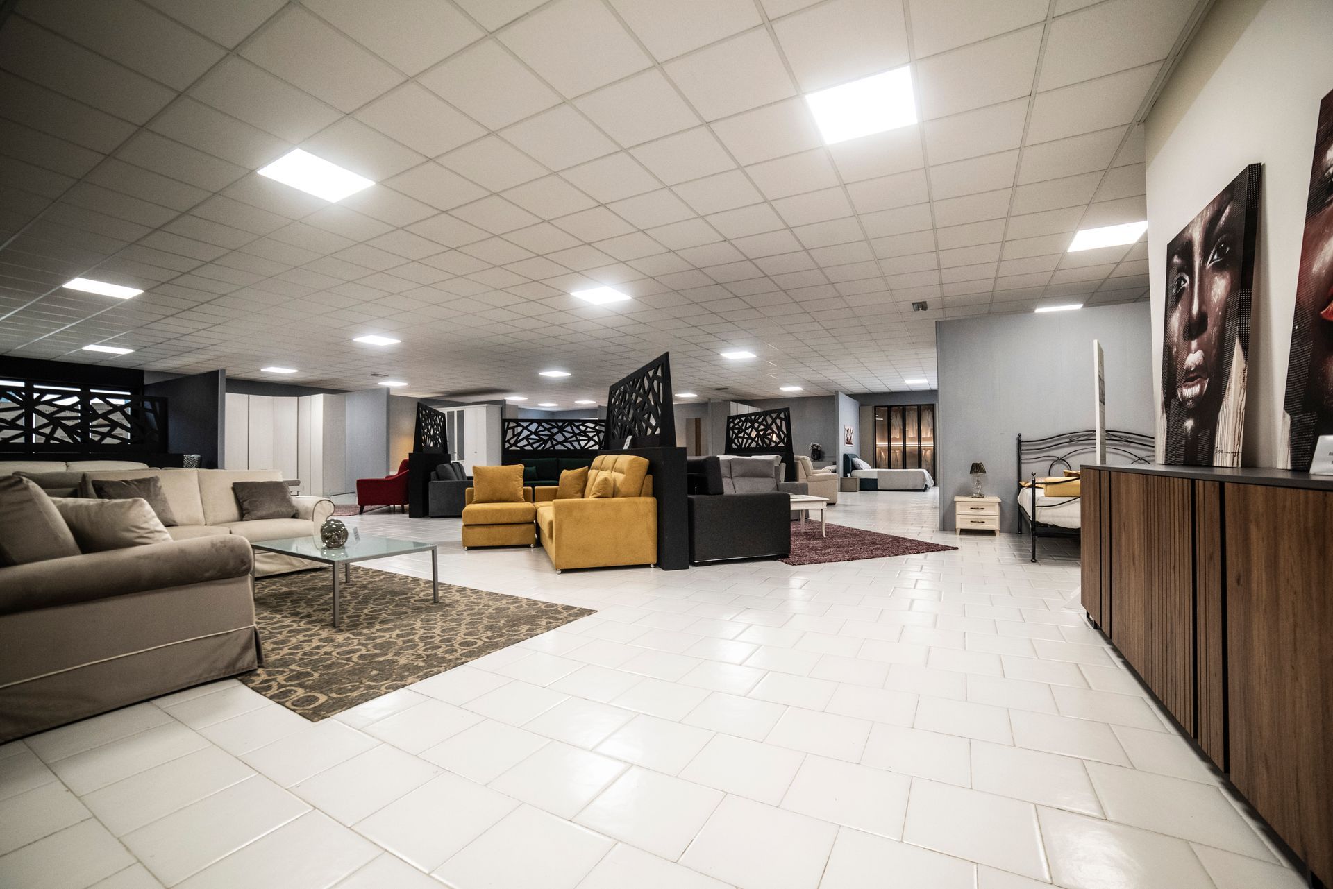 Showroom di mobili con divani, sedie, opere d'arte e pavimento piastrellato.