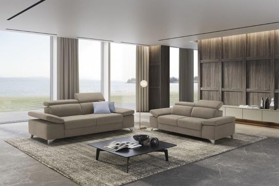 Soggiorno con divani beige, tappeto, tavolino da caffè e ampie finestre con vista sull'oceano.